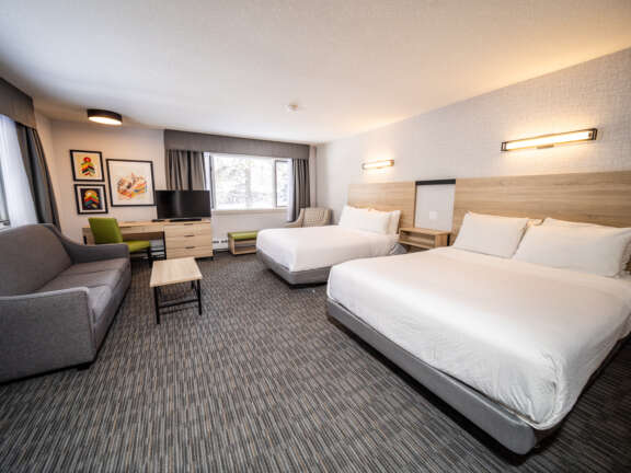 Family room with two queens and a sofa bed at Mountaineer Lodge, Lake Louise, sleeps six across Main Lodge and Timber Building.