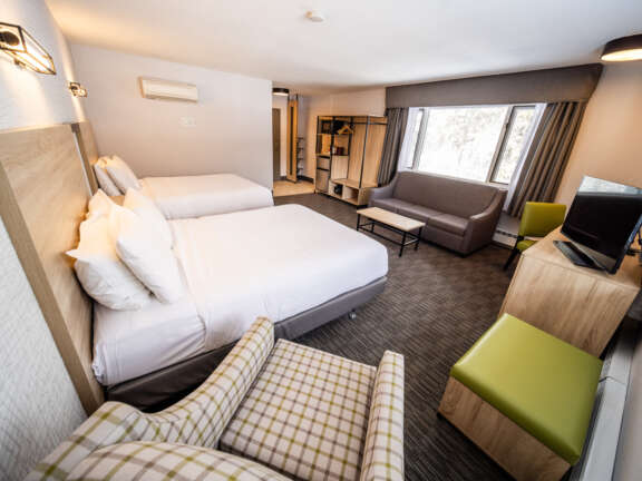 Family room with two queens and a sofa bed at Mountaineer Lodge, Lake Louise, sleeps six across Main Lodge and Timber Building.