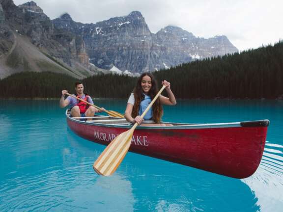 Image of 2 people canoeing in a red canoe on a stunning blue Moraine Lake