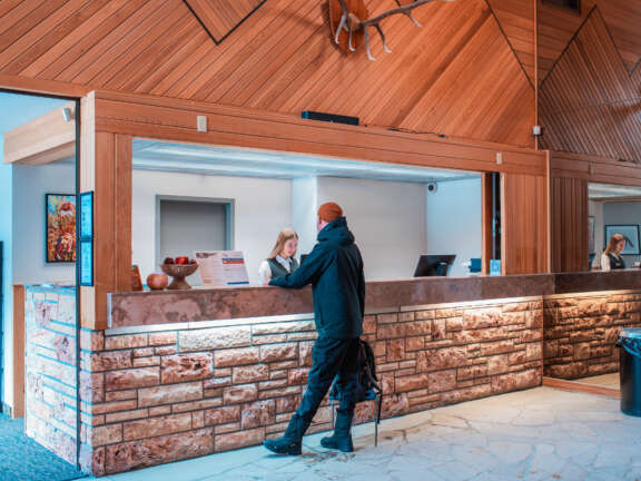 Guest chatting with a Guest Services team member at the Mountaineer Lodge Front Desk.