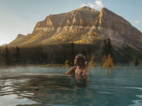 A guest enjoys a soak in the spa in Lake Louise with a stunning mountain view.