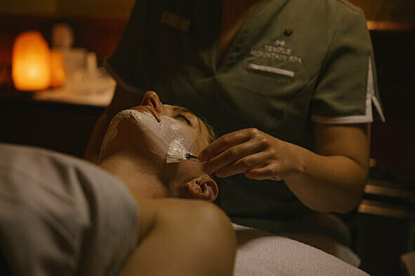 Esthetician giving a relaxing facial spa treatment at a spa in Lake Louise.