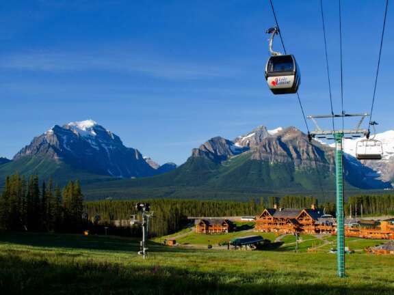 Blue sky over Lake Louise ski resort, showing enclosed gondola up to the summit.